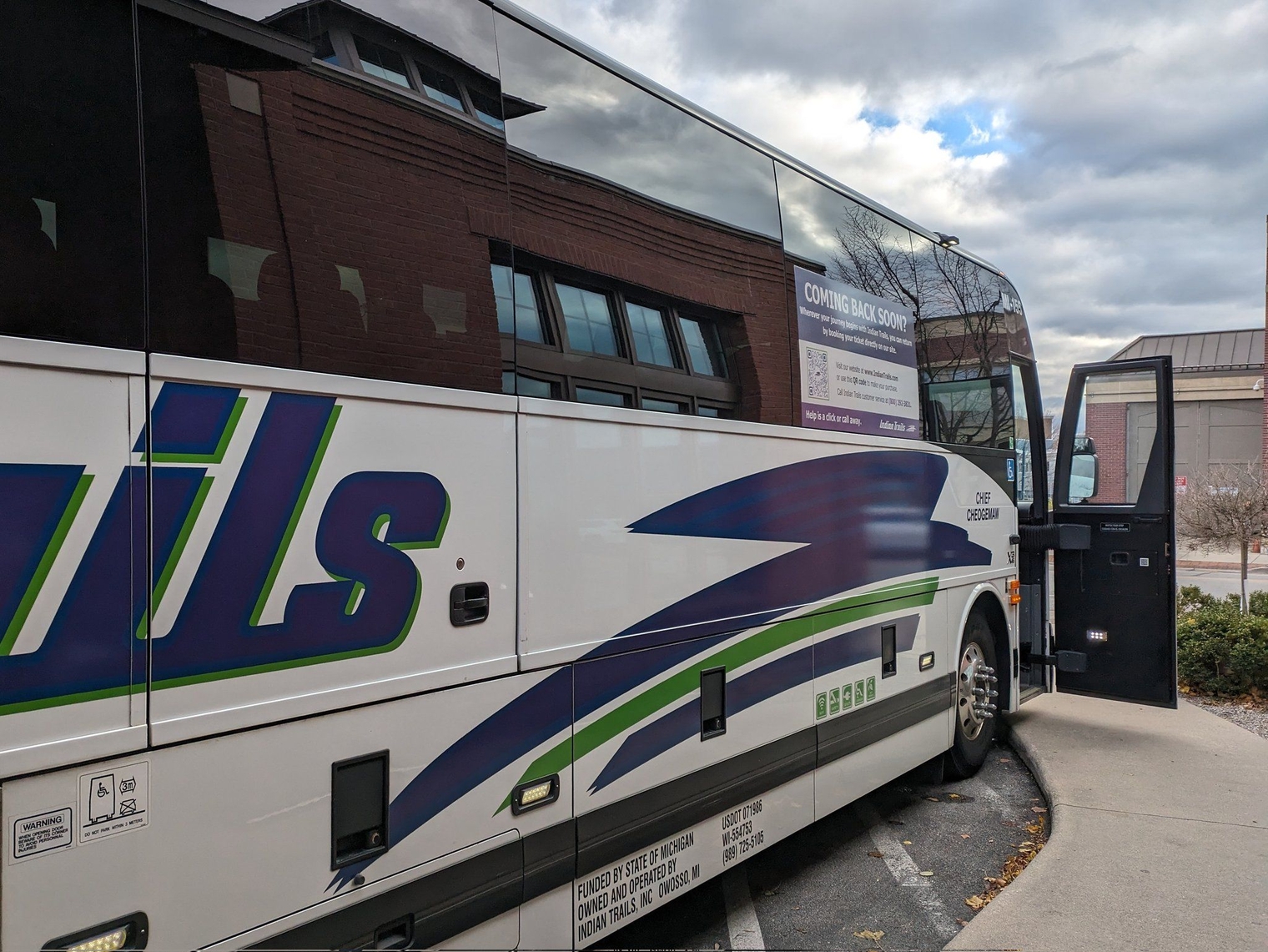 The Indian Trails bus at the station with its door open. The purple and green swoosh mark on the bus is in center frame