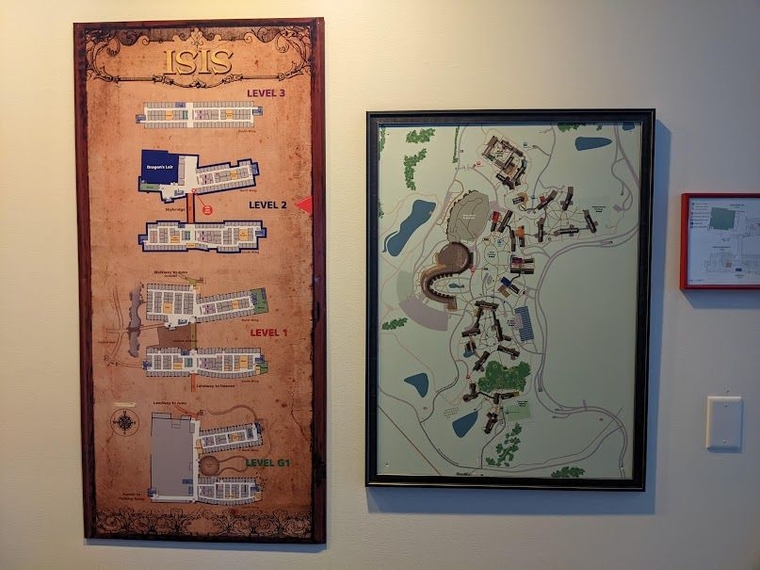 A framed map on the wall of a building with four floors alongside a second map of the entire campus