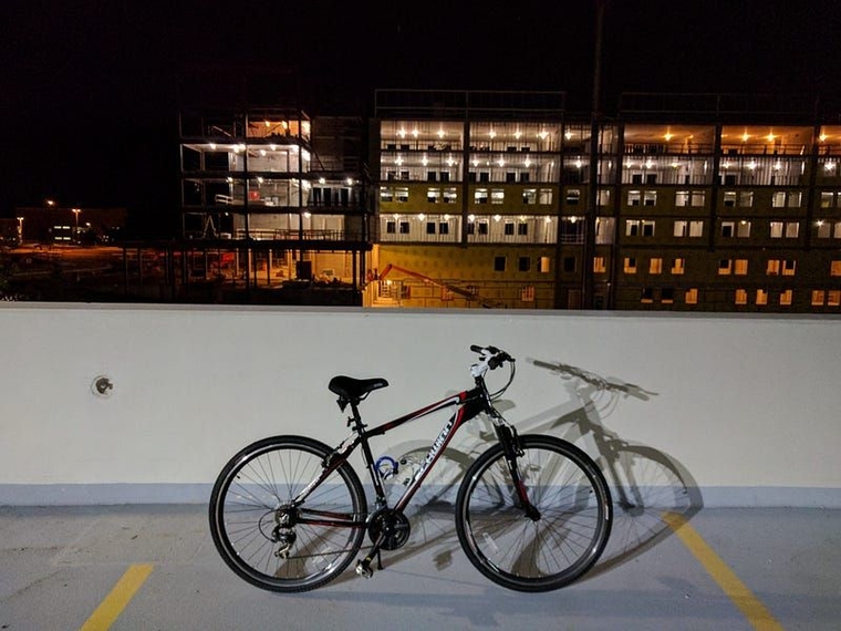 My bicycle atop an Oakland University parking structure at night, with a dorm under construction in the background