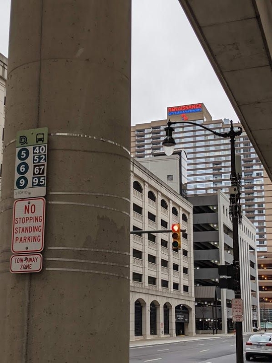 The bus stop at Larned and Woodward with a sign showing the seven routes that serve it.