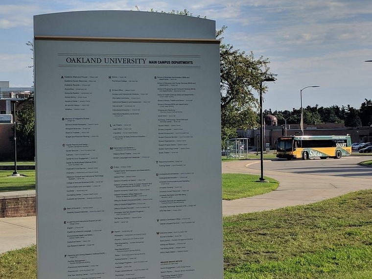 A bus visible behind an Oakland University wayfinding sign