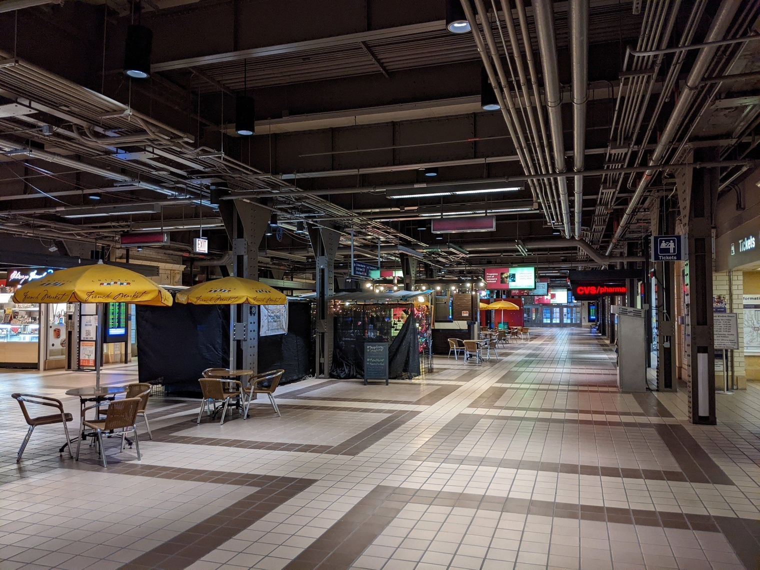 Metra Market on the north side of Ogilvie Transportation Center, beneath track level. Tables with umbrellas are in the center of the concourse.