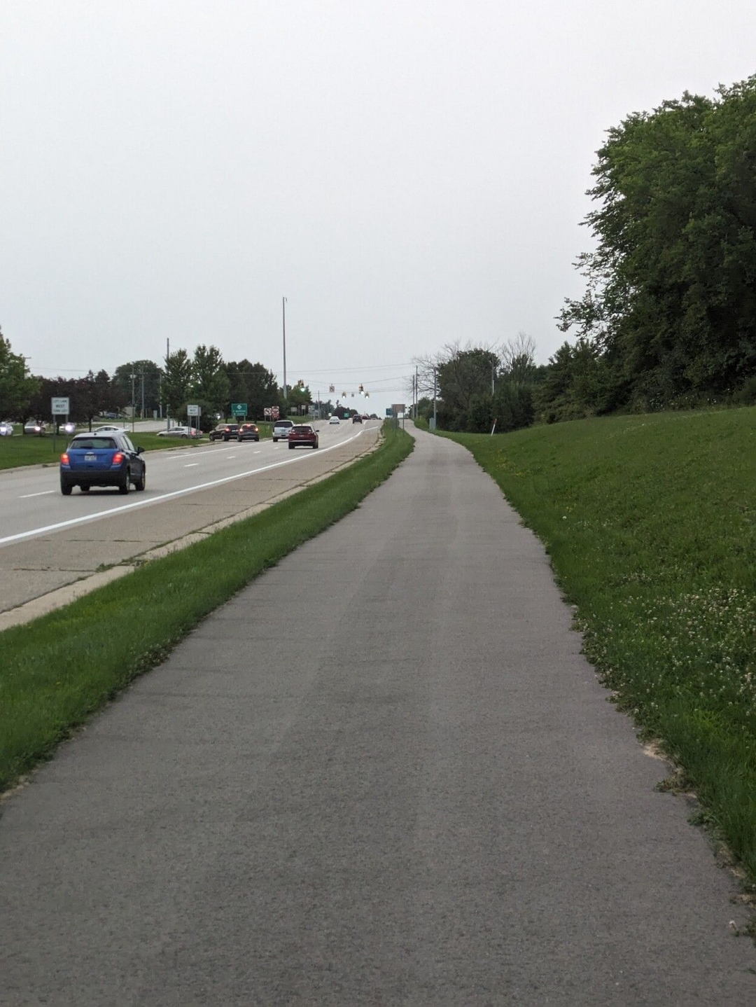 Blacktop pathway right alongside a four lane divided highway