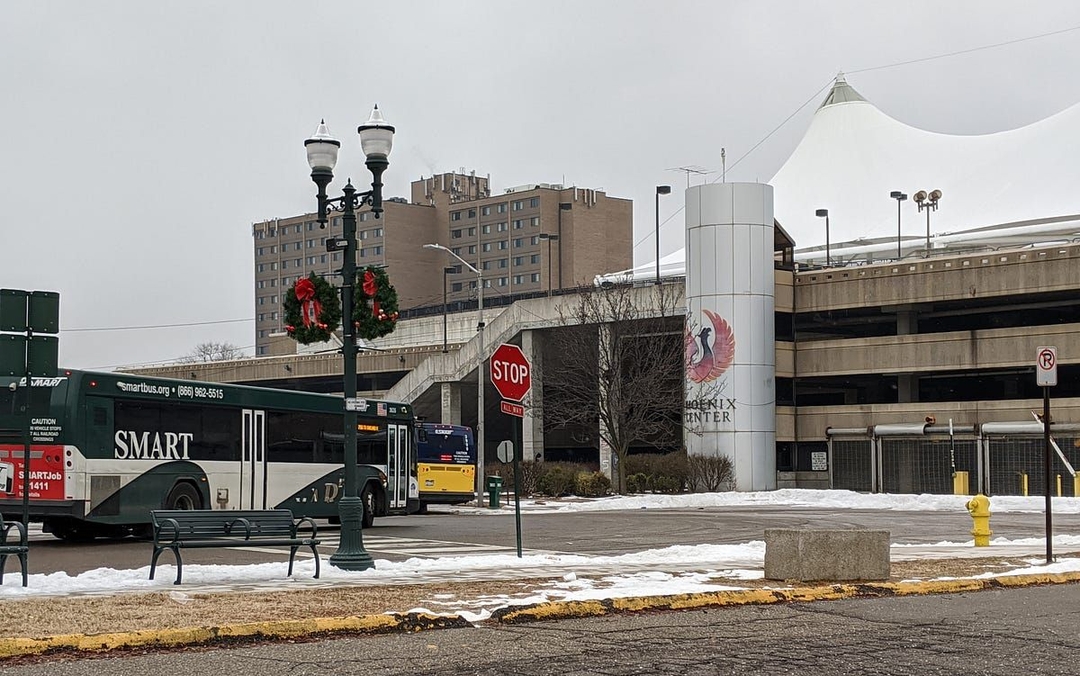 Two buses pulling outside the Phoenix Center parking structure on an overcast day