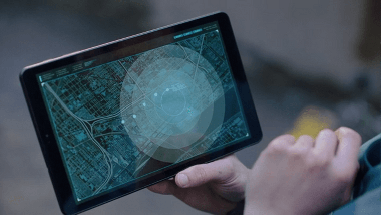 An actor holding a tablet displaying a stylized map of downtown Detroit