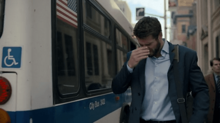 Dodge stepping off a city bus with a blue stripe and an American flag on the back window