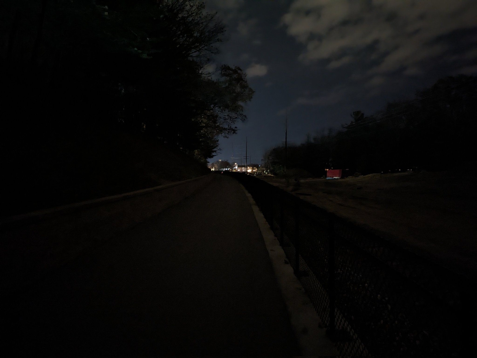 Walking uphill with the lights of a brewery far on the horizon