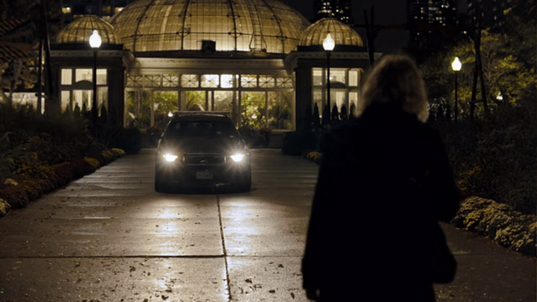 A large conservatory with a glass dome lit at night, with a police car out front