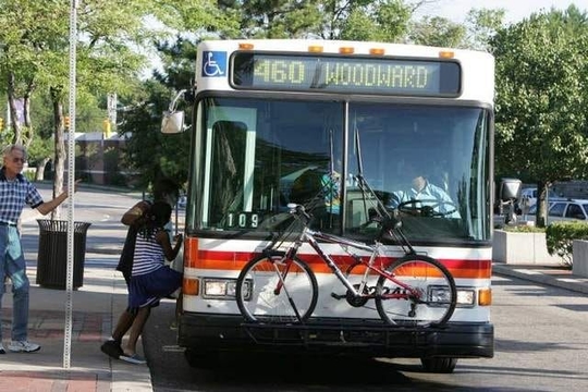 Riders board the Woodward Local at Royal Oak Transit Center. A bicycle is on the front rack of the bus.