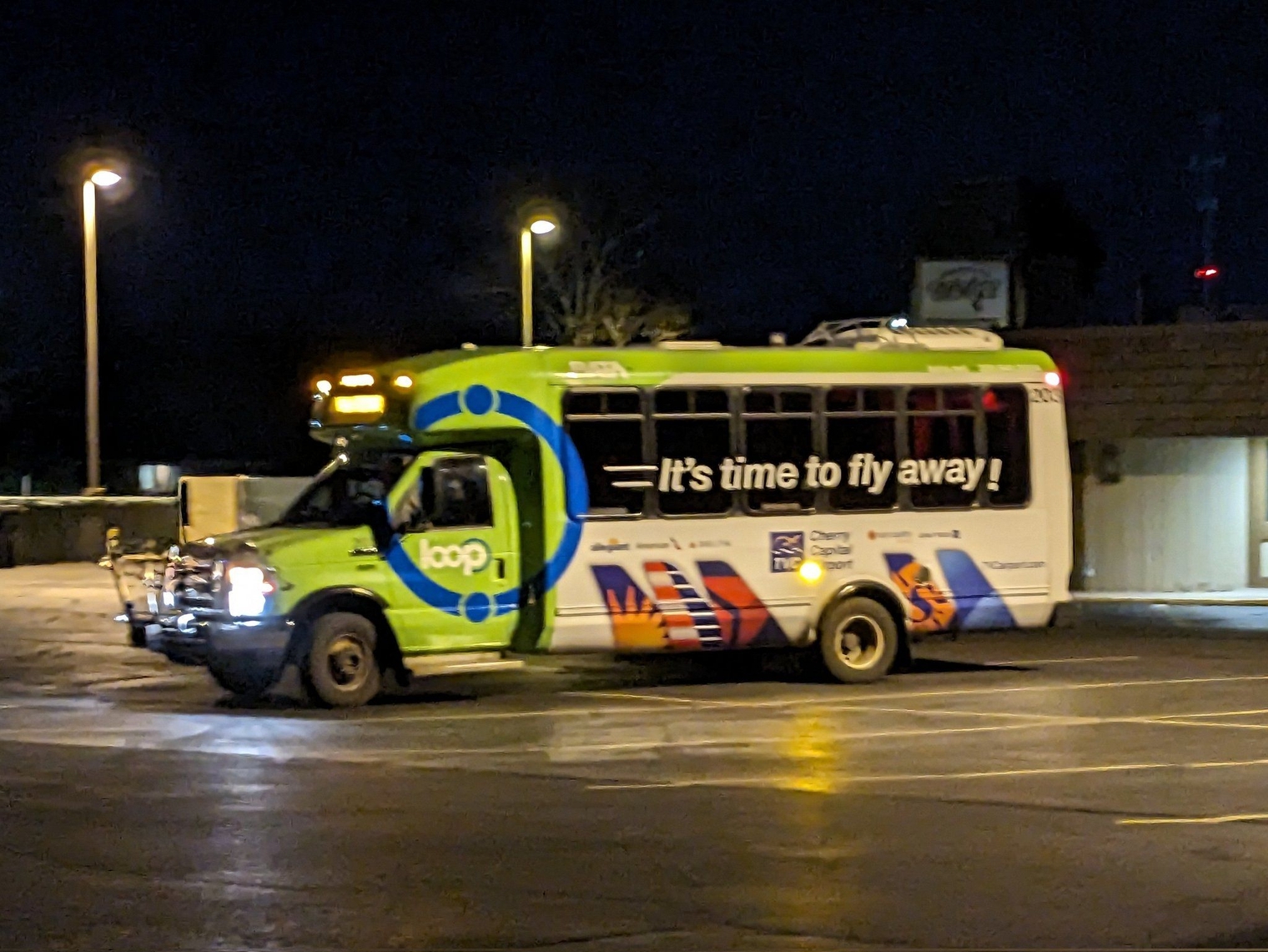 The cutaway bus with a wrap advertising the airport – "It's time to fly away!"