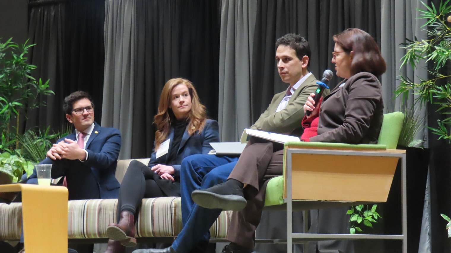 Representative Jason Morgan, Senator Mallory McMorrow, and Zach Kolodin look towards Megan as she moderates the legislative panel.