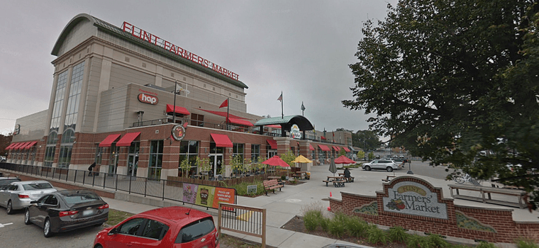 The new Farmers' Market, a multi-story building with red awnings and many benches and picnic tables outside the front entrance