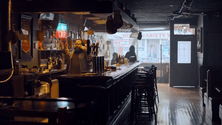 A small, empty bar with the bartender on the phone