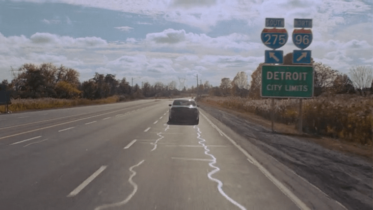 A car driving past a sign that reads “Detroit City Limits” and signs for South 275 and North 96