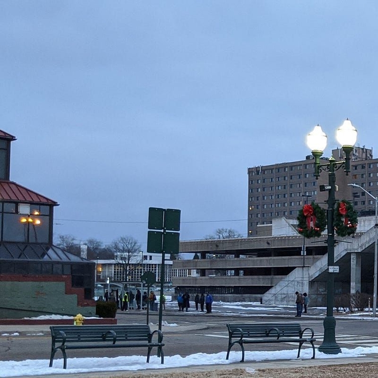 A crowd of people inside and around a shelter at dusk