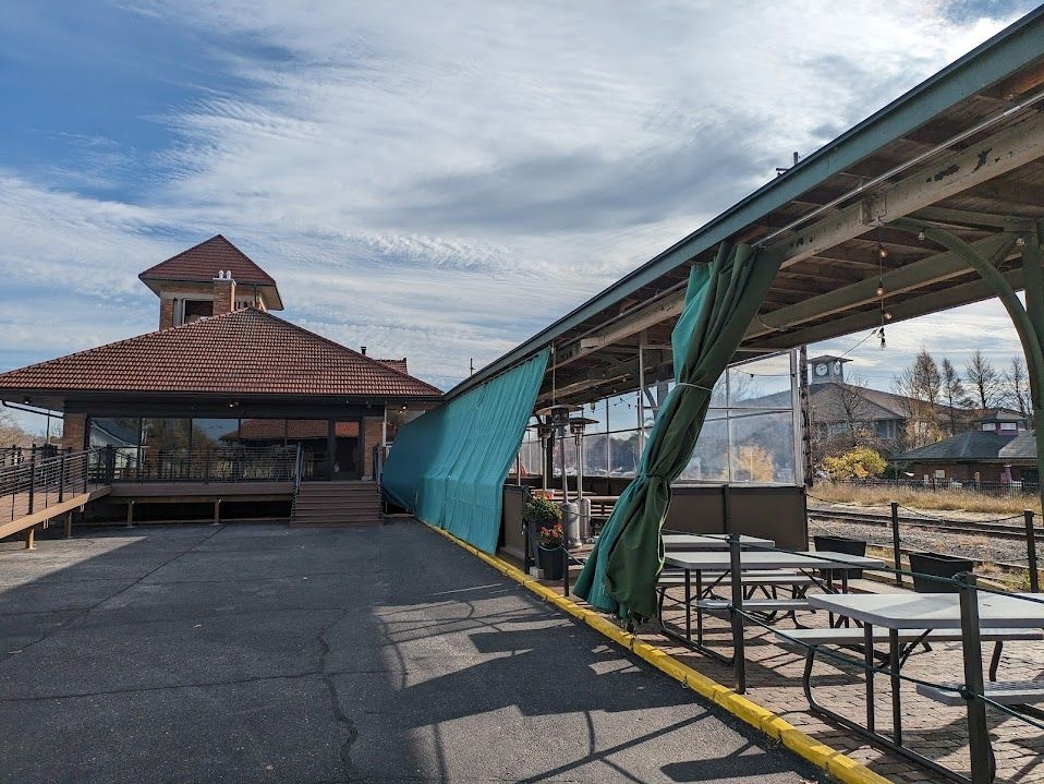 Several picnic tables enclosed in a green tarp underneath the saffolding for the old rail platform