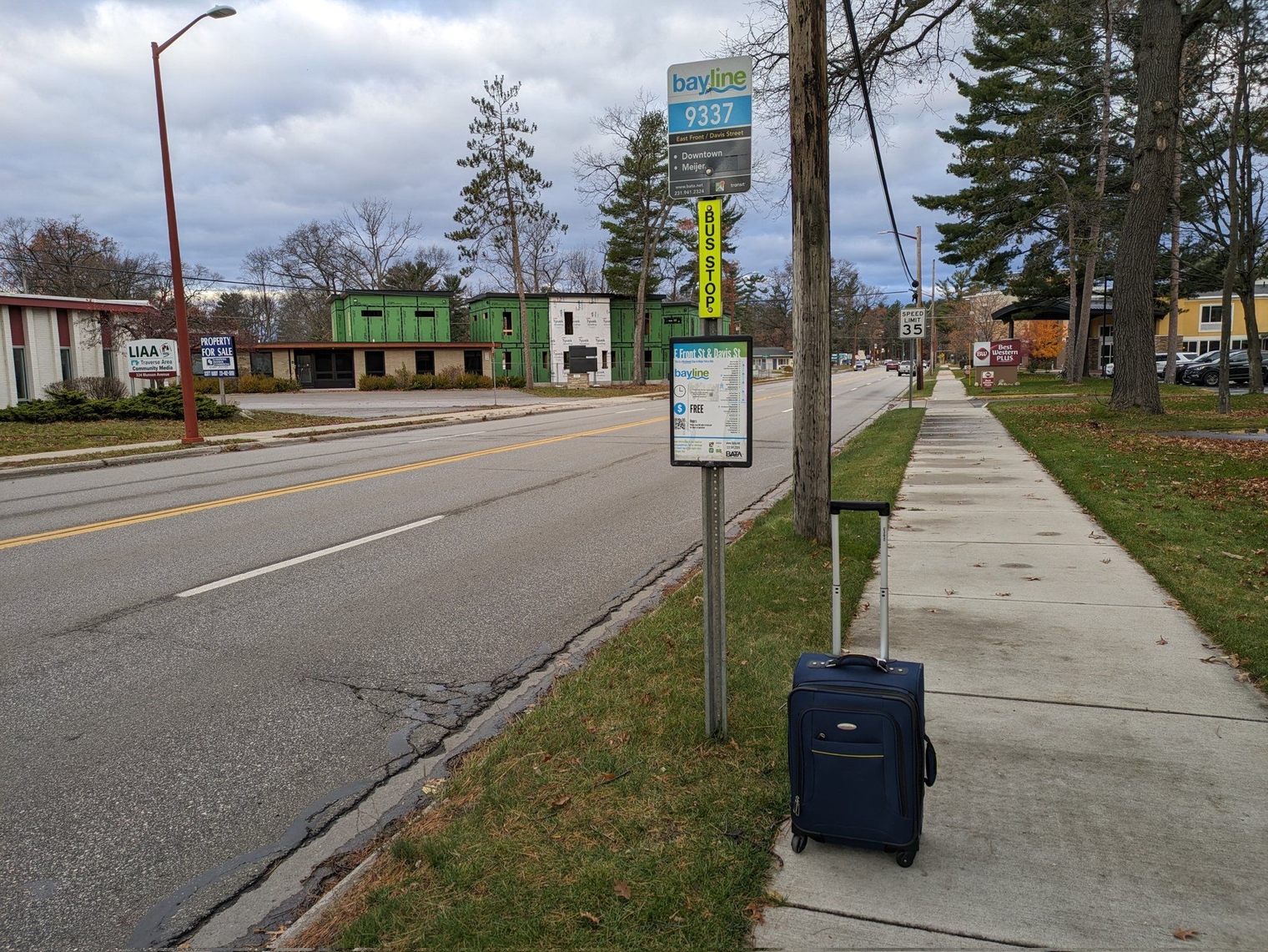 Bayline stop along a four lane road with no infrastructure, just a sign and a schedule