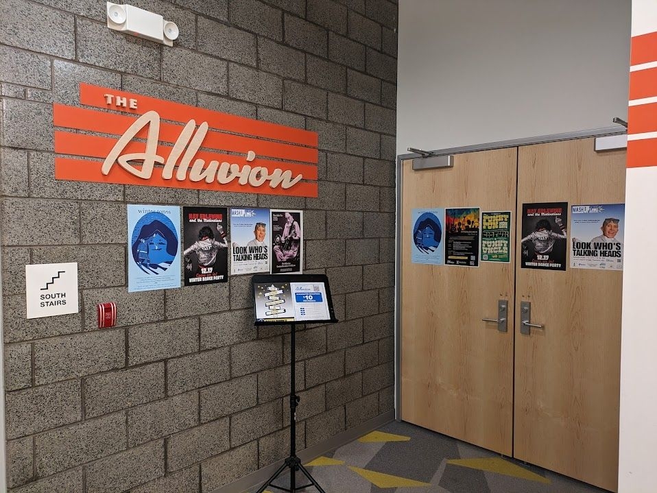 The doors to The Alluvion, a public theater which hosts local performing artists and various shows. Posters line the wall.