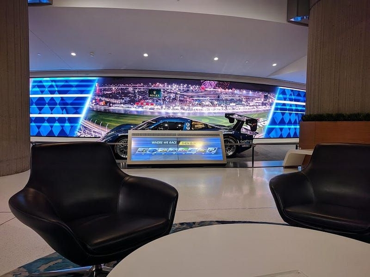 A racecar on display in the RenCen behind two black swivel chairs and a white table