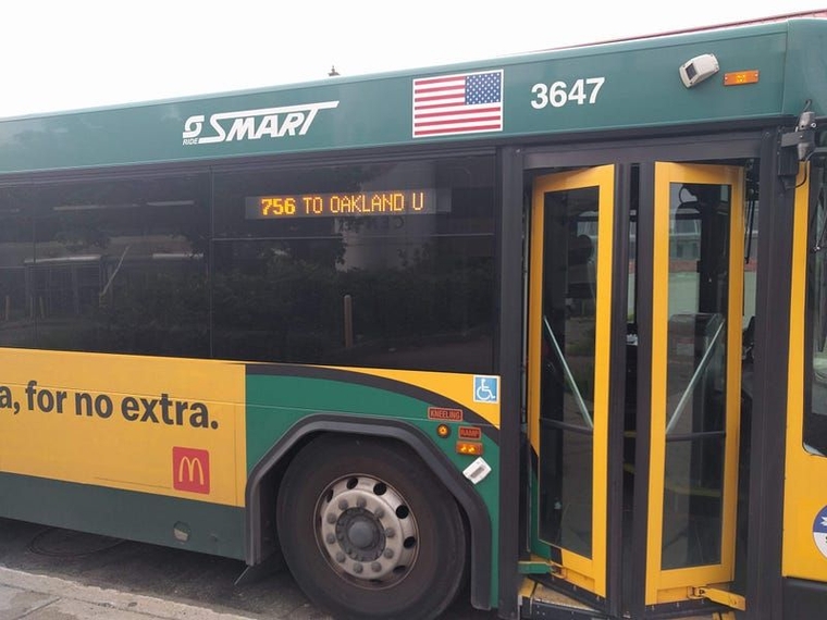 A green and yellow SMART bus with its front door partially open