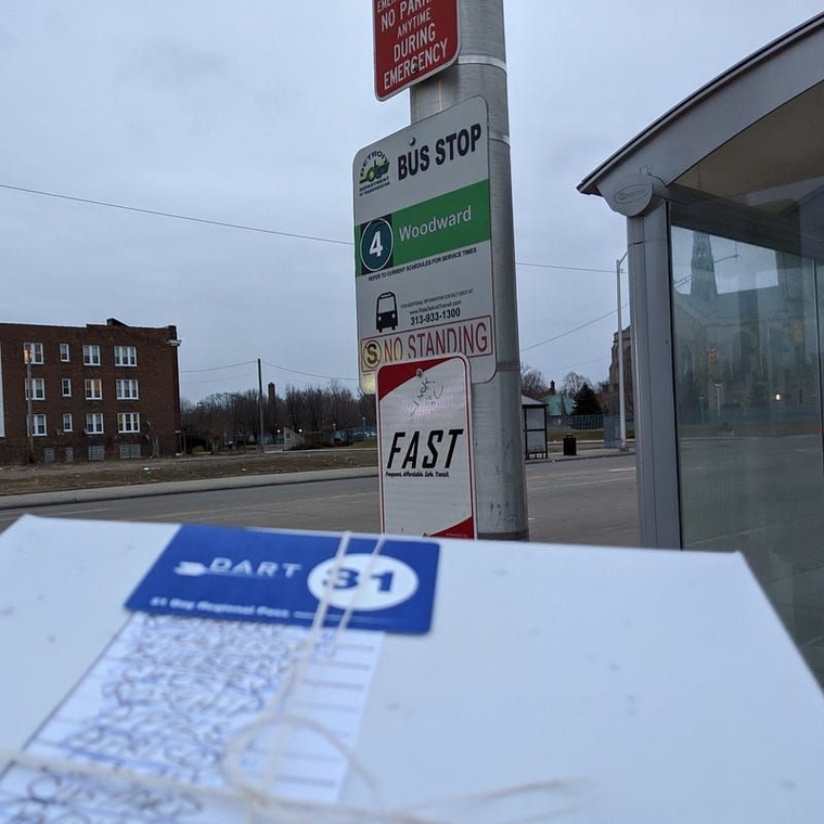 The box of paczki underneath the sign for DDOT Route 4 and FAST Woodward at Trowbridge.