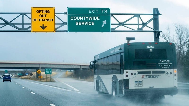 A SMART bus passes under two navigational signs on I-75 South. They've been edited to read "Opting Out of Transit" and "Exit: Countywide Service." The bus is exiting under the second sign.