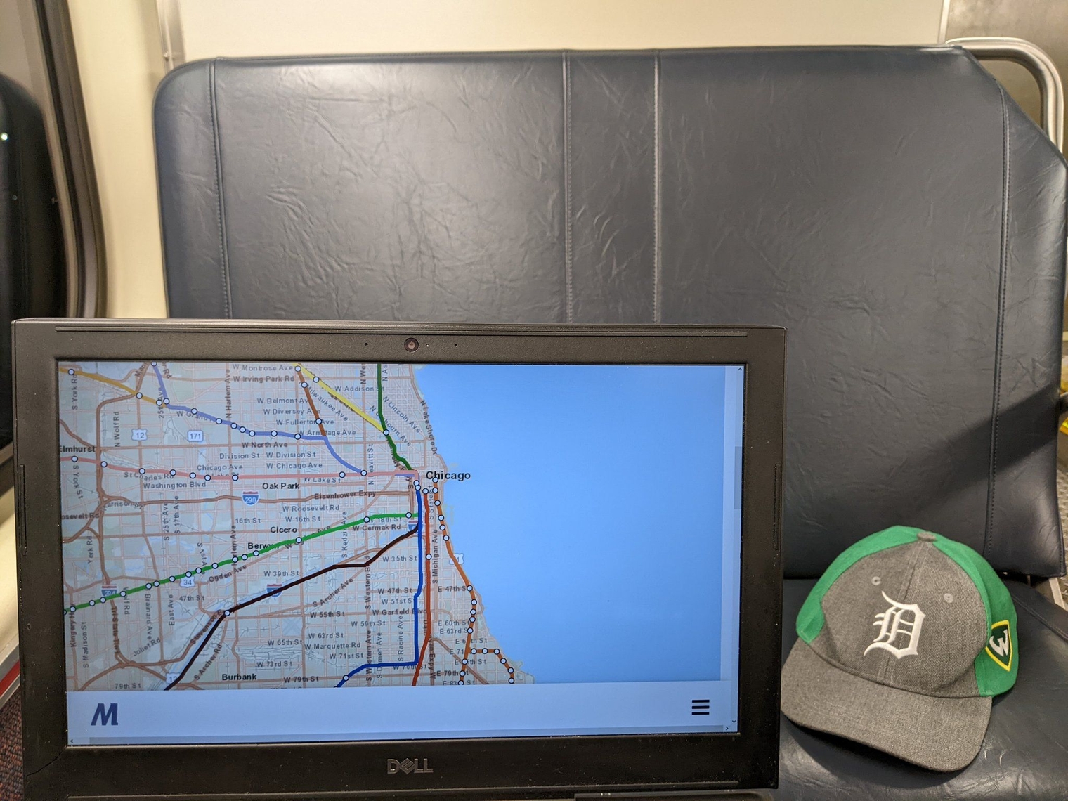 My computer next to my Wayne State Tigers cap sitting on the seat next to me