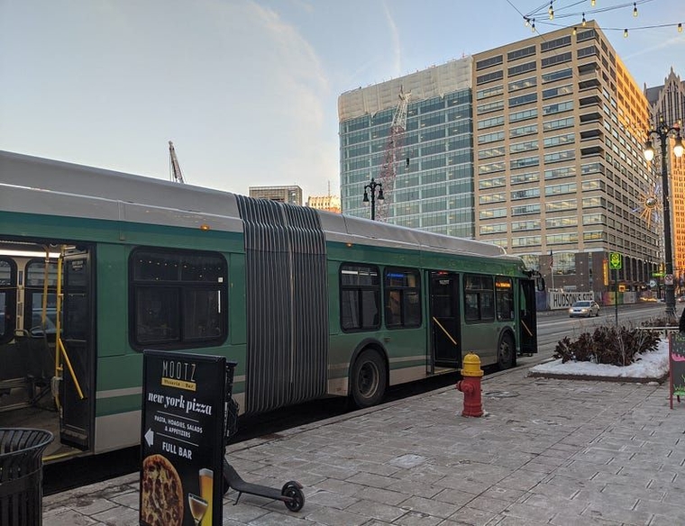 A green articulated DDOT bus on Woodward Avenue