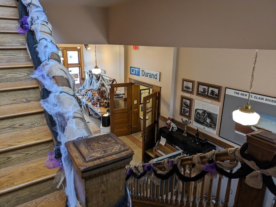 The interior staircase of Durand Union Station, looking down towards the first floor. Old train photos and Grand Trunk memorabilia line the walls.