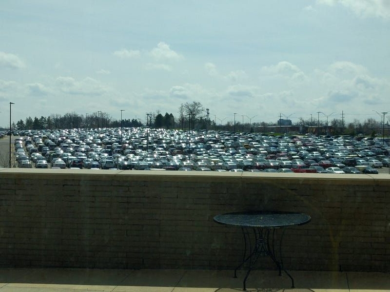 Hundreds of cars in a large parking lot shimmering in the sunlight.