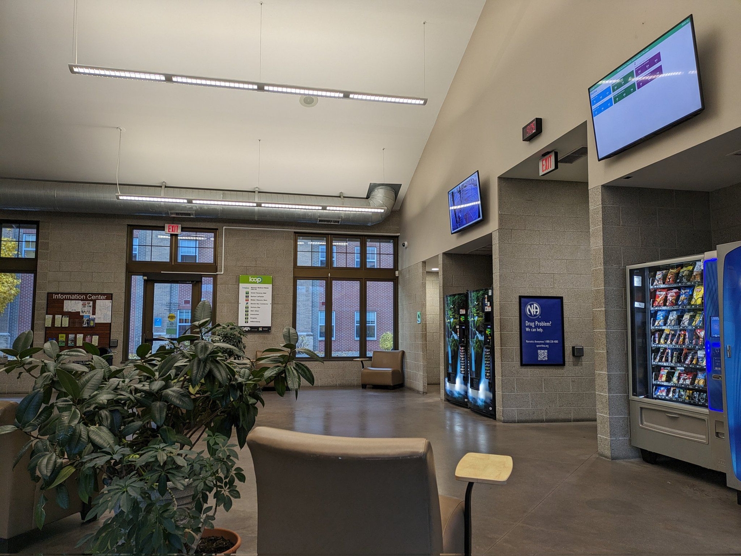 Interior of the bus station with vending machines, departure displays, and plants