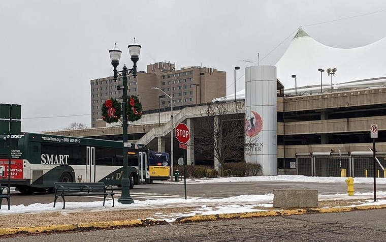 Two SMART buses turn left in front of one of the Phoenix Center's concrete staircases.