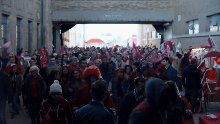 A huge crowd dressed in Red Wings apparel in a narrow outdoor walkway between buildings