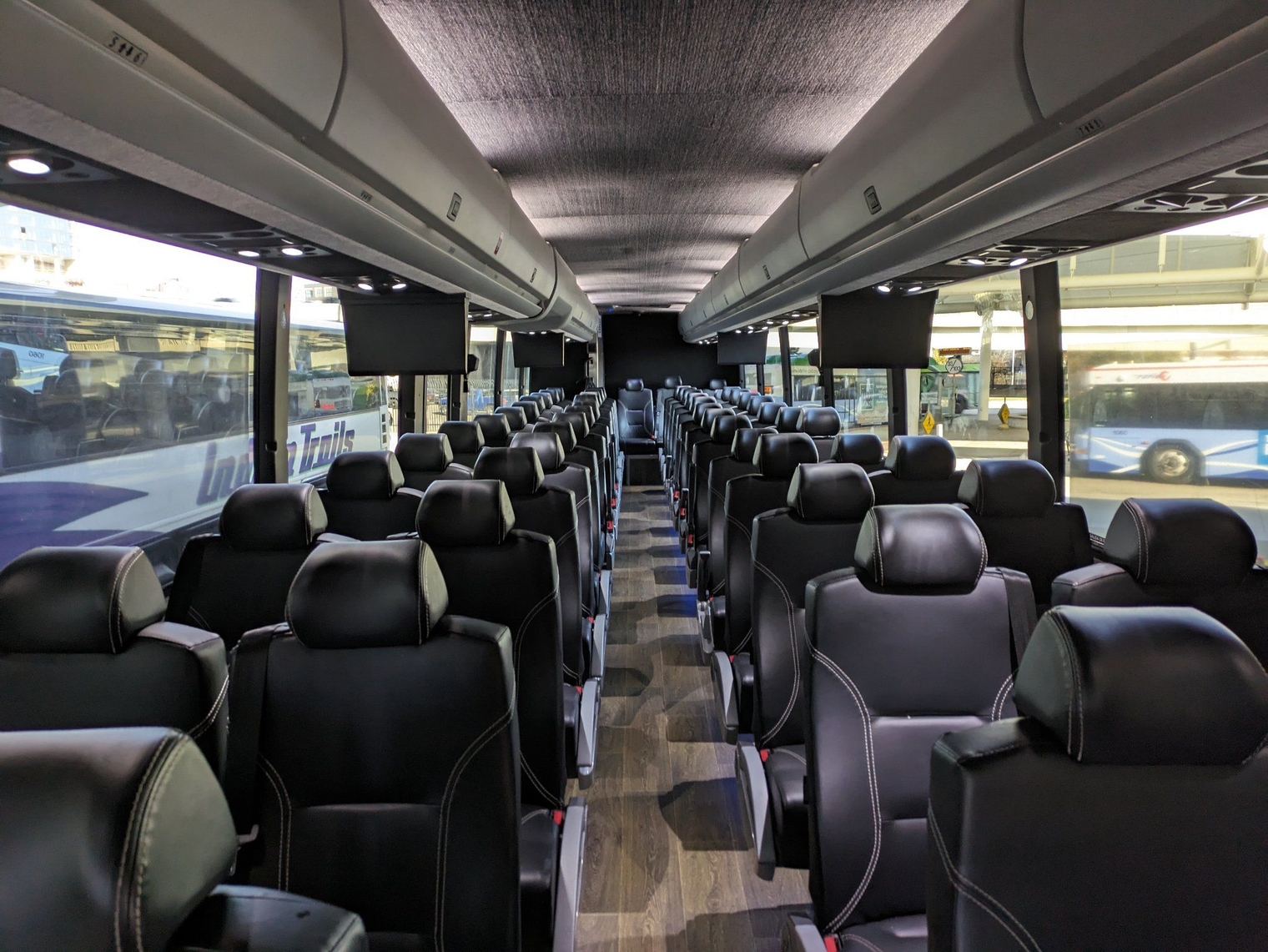 The black leather bus seats, looking towards the back from the front of the bus