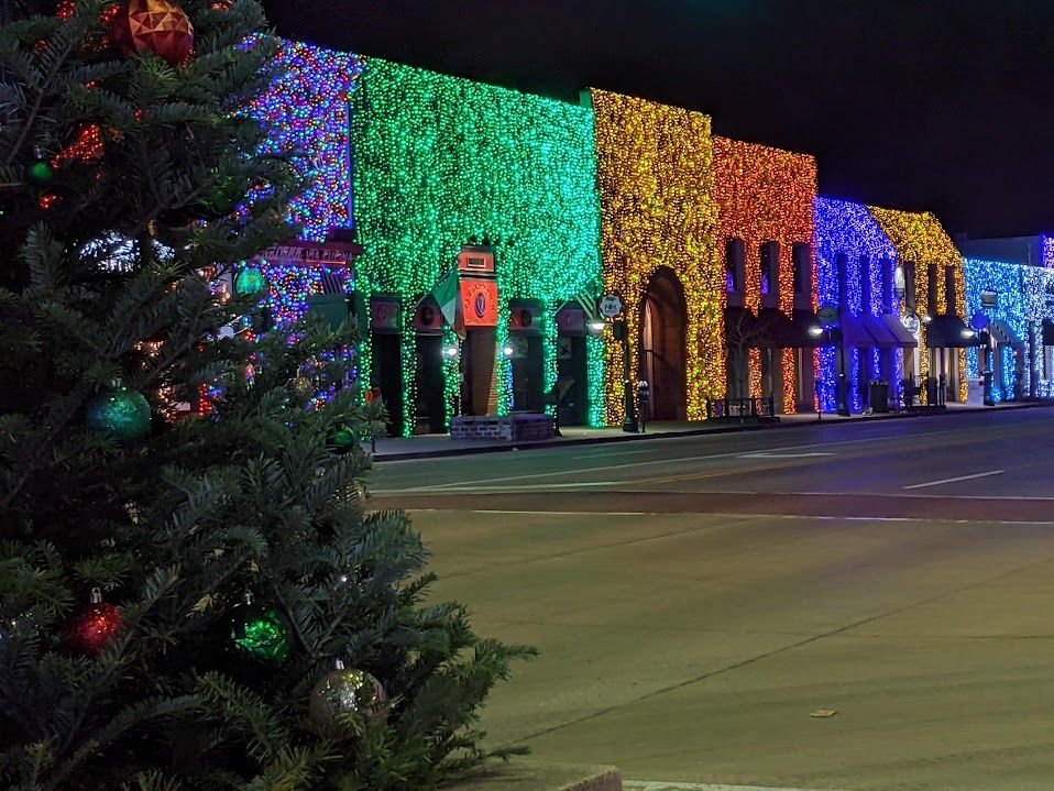 A Christmas tree in front of multi-colored lights covering the facade of every building along Main Street in Downtown Rochester