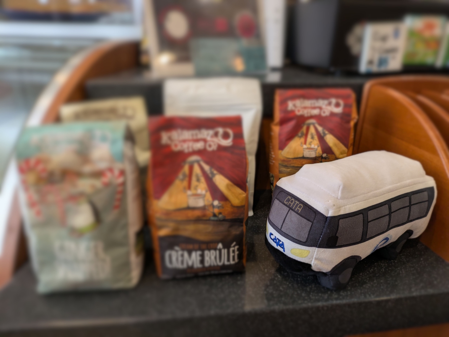 A plushie CATA bus from the Transit Day at the Capitol vehicle showcase next to bags of coffee inside the Hob Nob