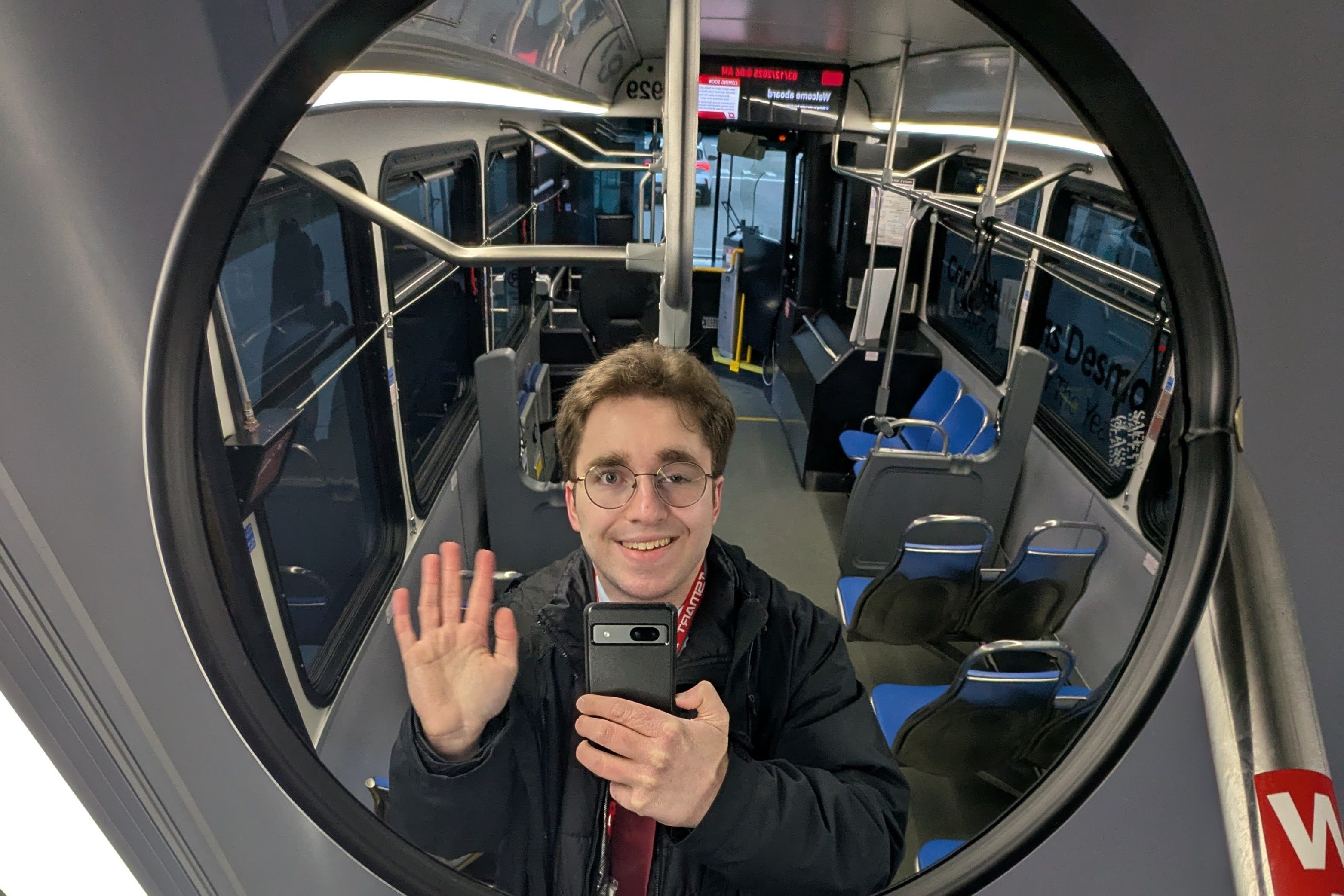 Me waving in the rear-door mirror of a SMART bus staged in Lansing for Transit Day at the Capitol