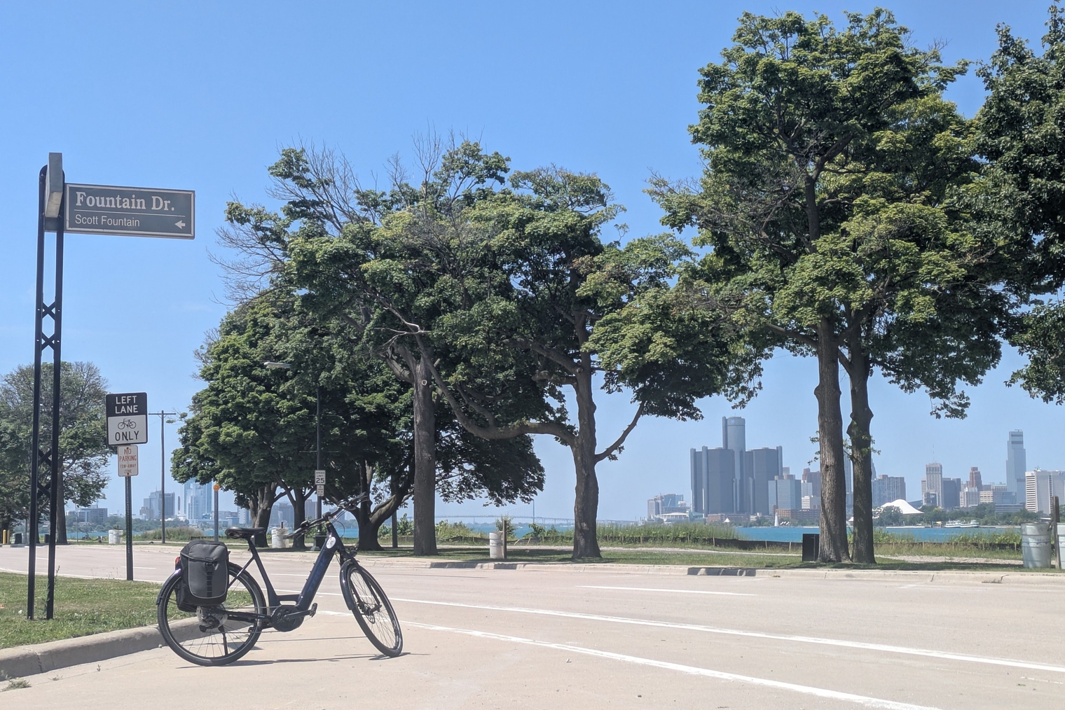 My new Trek e-bike on Sunset Boulevard with the RenCen in the background, in the exact same location as this page's cover photo with my e-Sparrow in 2022