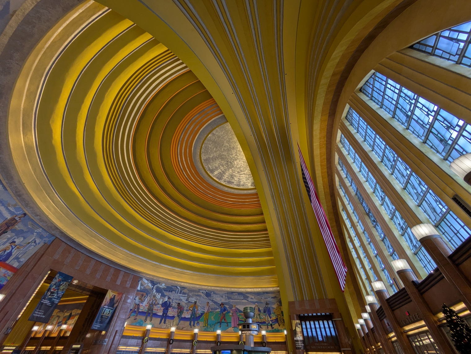 Looking up at the historic vaulted dome in the atrium of Cincinnati Union Terminal with a curved mural and large stained glass window beneath it