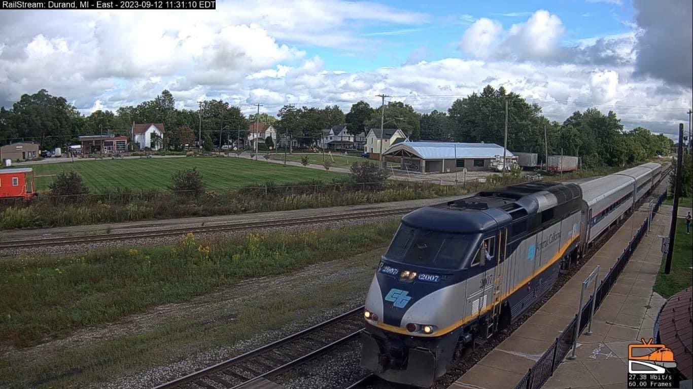 An Amtrak California locomotive pulling three Horizon coach cars passes through Durand.