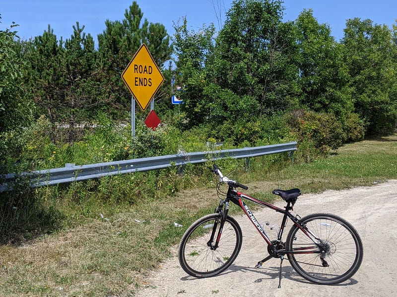My red and black Schwinn 21-speed bike on Reid Road next to Interstate 475 in Grand Blanc Township. A sign reads "ROAD ENDS."