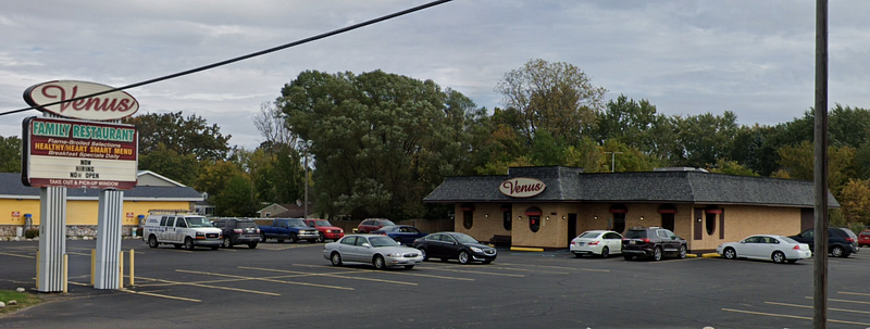 A small family restaurant in a brick building with a large sign in the parking lot that reads "Now Hiring / Now Open"