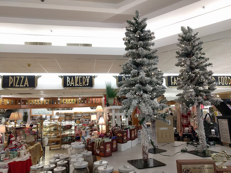 Interior with various displays of wine and Christmas gifts next to two small trees with white lights