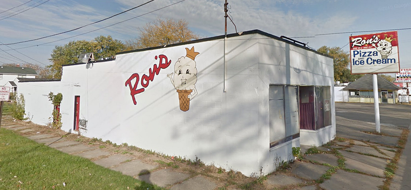 A smiling ice cream cone painted onto the side of a white brick building